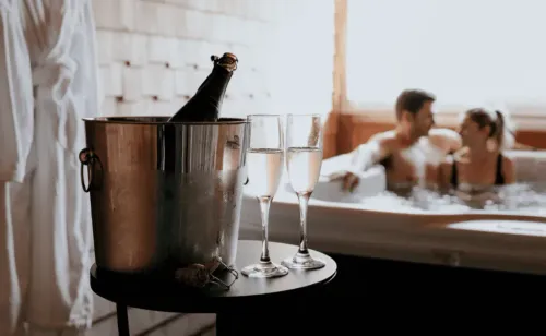 Couple Sitting in the hot tub with a bottle of champagne on ice and two flutes at The Wentworth, Jackson, New Hampshire